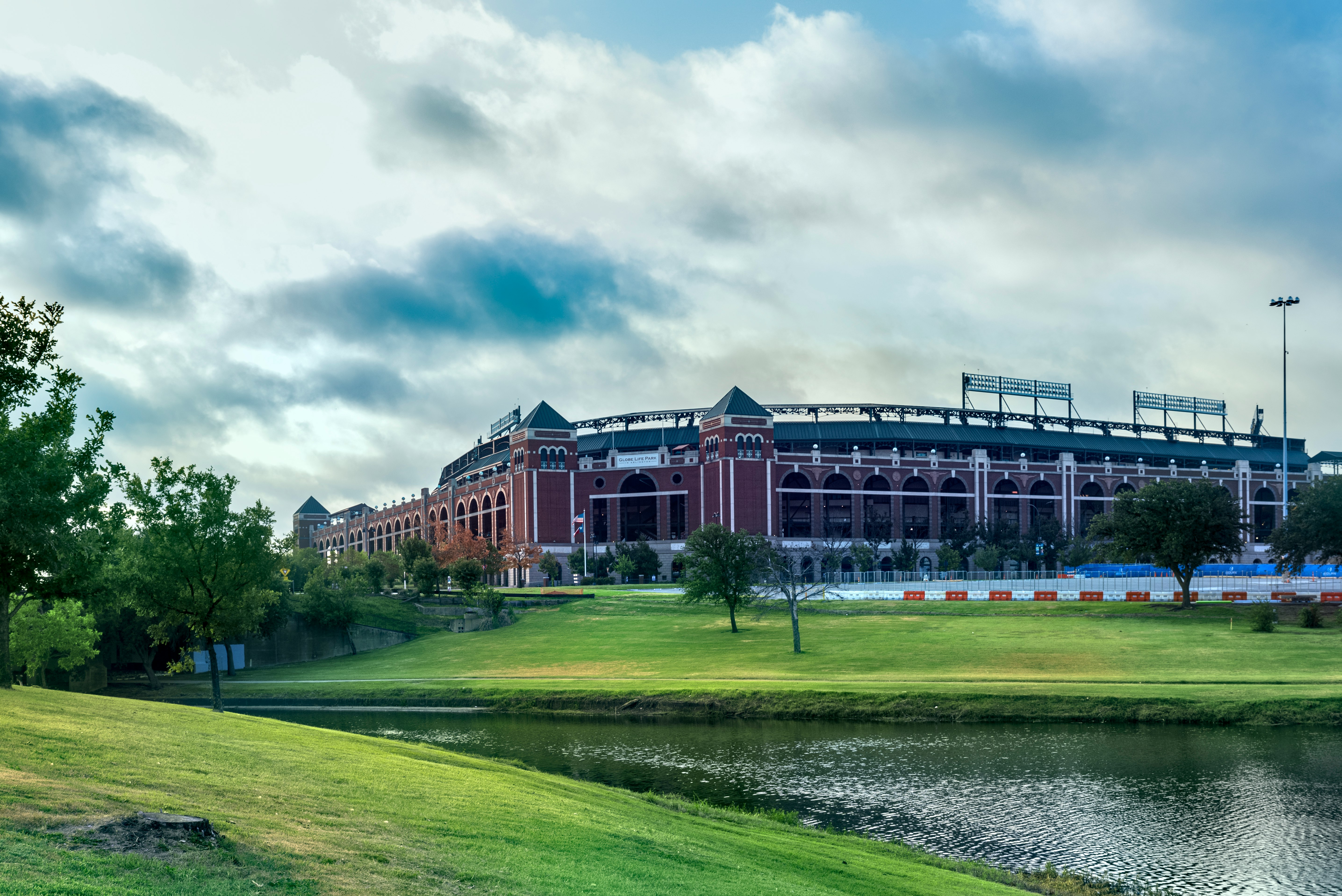 brown and white concrete building near green grass field under white clouds during daytime